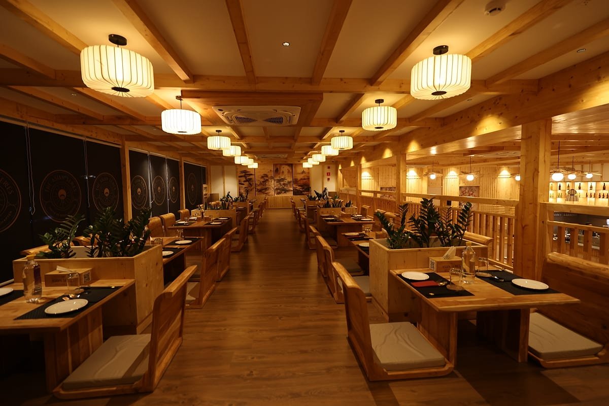 The dining room in Mysuru — booths and planters beneath a row of paper lanterns