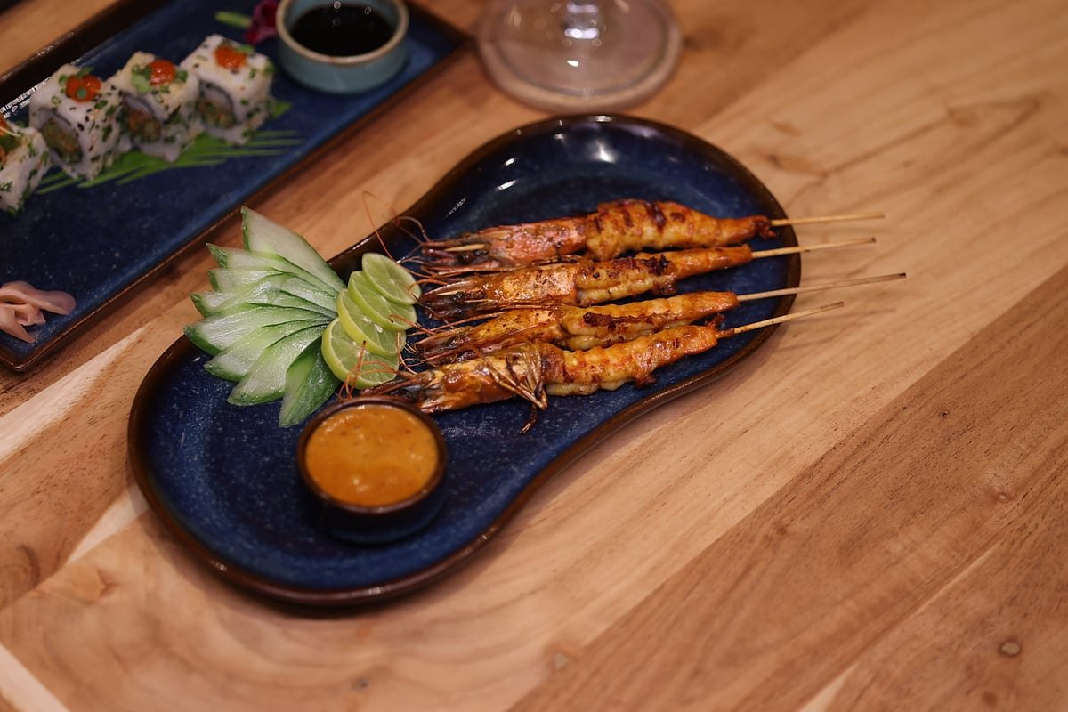 Satay and maki together on a wooden table